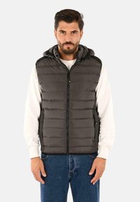 Gilet imbottito grigio scuro con cappuccio, dotato di una chiusura con zip, due tasche laterali e una texture trapuntata. Ideale per essere indossato a strati sopra gli abiti.
