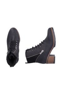 Bottes chelsea noires avec lacets, fermeture éclair sur le côté, en cuir synthétique texturé, et un talon bloc marron contrastant. Présente des œillets en métal et une languette.