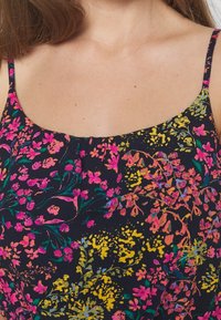 Blommönstrad tyg i marinblått med livfulla rosa, gula och gröna blommor. Har tunna axelband och en rundad halsringning.