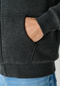 Dunkelgraue Zip-Hoodie mit Fronttasche, gerippten Bündchen und Saum, aus strukturiertem Fleece-Material gefertigt.