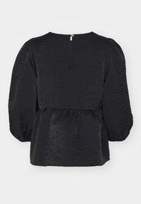 Blouse noire texturée avec manches longues bouffantes, taille froncée et petite fermeture par bouton au dos de l'encolure.