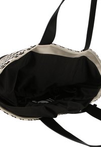 Torebka tote w czarno-białym wzorze z teksturowanym wykończeniem, przestronnym czarnym wnętrzem z materiału oraz dwoma mocnymi czarnymi uchwytami.