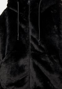 Černá vesta z umělé kožešiny se zipem vpředu, nastavitelnou kapucí se stahovací šňůrkou a dvěma předními kapsami. Měkká textura s plyšovým povrchem.