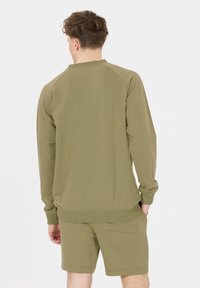 Olivgrön sweatshirt med rund hals, raglanärmar och ribbad nederkant, tillsammans med matchande shorts som har en bakficka.