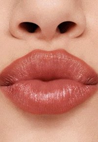 Glanzende nude lipkleur met een volle, gladde textuur. De lippen worden geaccentueerd met een subtiele glans, en benadrukken een natuurlijke huidtoon tegen een neutrale achtergrond.