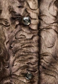 Cappotto in pelliccia sintetica marrone con texture ondulate, con un bottone nero lucido che valorizza il design e offre un dettaglio funzionale.