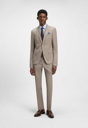 Beige suit with a textured finish, single-breasted jacket, matching trousers, light blue shirt, and polka dot tie. Brown dress shoes.