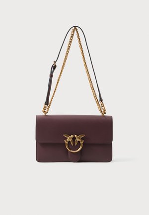 Temno burgundska usnjena torba za ramo z zlatim verižnim trakom in zlatim obročem za zapiranje, ki ima dva ptica, ki se gledata.