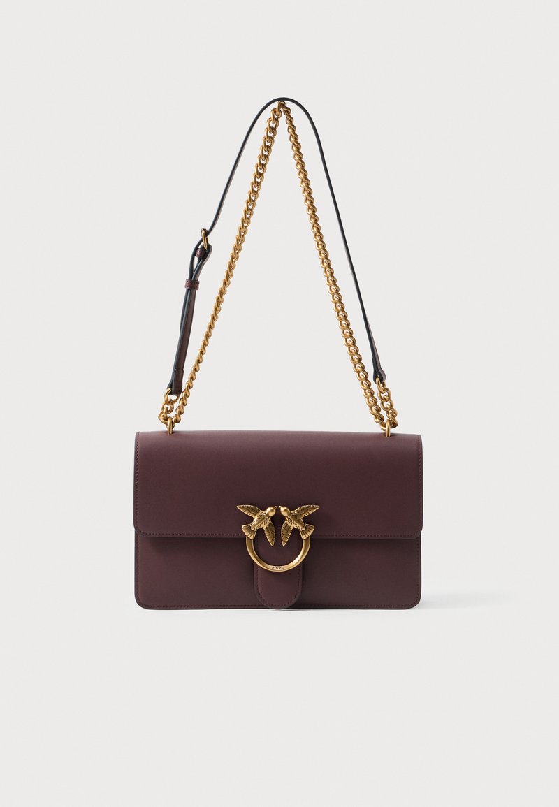 Bolsa de ombro em couro bordô escuro com alça de corrente dourada e fecho de anel dourado, apresentando duas aves voltadas uma para a outra.