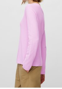 Jersey de punto color rosa claro con mangas largas y un ajuste holgado. Presenta una tela texturizada, escote redondeado y un dobladillo recto.