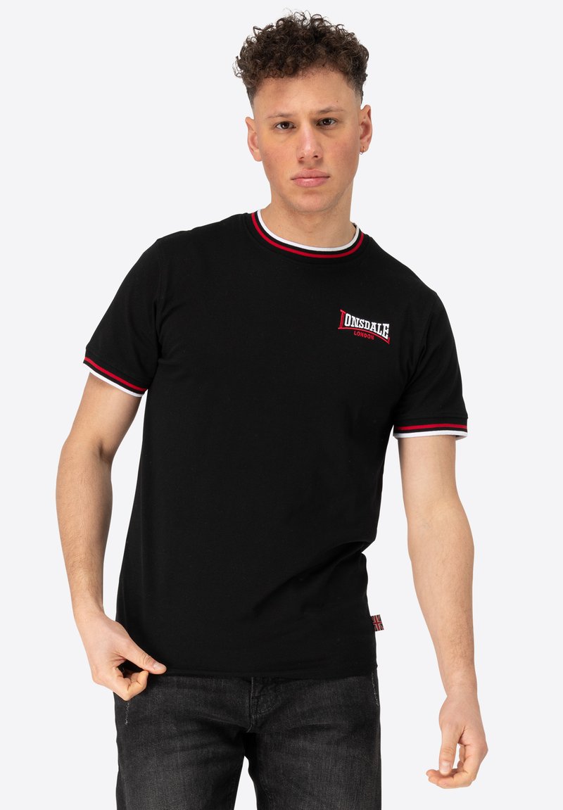 Musthave musta lühikeste varrukatega T-särk punase ja valge triibulise soonikkoes krae ning varruka servadega. Rinnal rikkalikult broderitud "Donsdale London" logo.