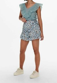 Světle modrá blůza s volány, výstřihem do V a krátkými rukávy, spojená s sukni s vysokým pasem s modro-černým leopardím vzorem.