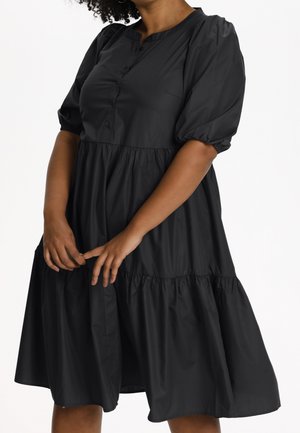 Schwarzes Kleid mit rundem Ausschnitt, Knopfverschluss und Puffärmeln. Es hat ein gestuftes Design und einen vollen Rock, gefertigt aus einem glatten Stoff.