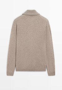 Beige stickad tröja med sjalkrage, långa ärmar, ribbade muddars och nederkant. Mjuk textur, sömlös design med minimalt med detaljer på baksidan.