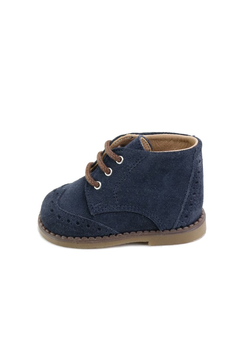 Zapato de ante azul marino con cordones y detalles de brogue, con suela cosida en color marrón claro y cordones marrones, que presenta una puntera redonda y altura hasta el tobillo.