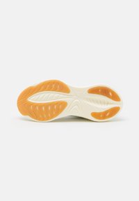 Suola di una sneaker con una base bianca strutturata e una suola in gomma arancione, progettata per aderenza e comfort. Visibili linee e motivi curvi.