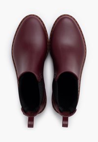Bottines en cuir bourgogne imperméables avec une surface en caoutchouc lisse, des panneaux latéraux élastiques, et des coutures tan contrastantes le long des semelles.