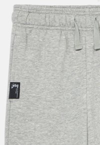 Light gray sweatpants with elastic waistband, drawstrings, side pocket, and small black Disney tag featuring Mickey Mouse outline.