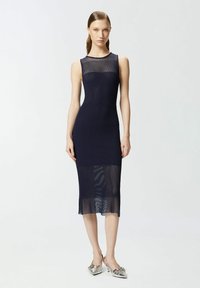 Morska plava rebrasta midi haljina s prozirnim dijelom na izrezu i lepršavim rubom. Uparena sa srebrnim cipelama na petu. Glatka tekstura.