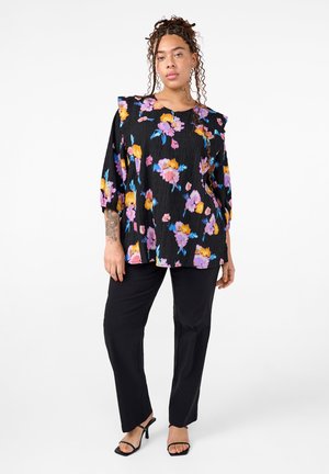 Black floral top featuring purple, pink, and yellow flowers, with a textured fabric, ruffled shoulders, and paired with black pants and sandals.
