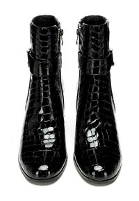 Botas de tobillo de charol negro con textura de cocodrilo, cuentan con una cremallera lateral y un acento de hebilla. Diseño de punta redonda.