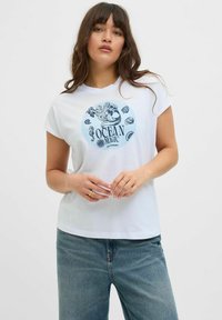 Bílý bavlněný tričko s krátkým rukávem, na kterém je modrá kruhová grafika s tématem oceánu, která zahrnuje mušle a text "OCEAN MAGIC."