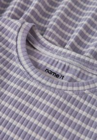 T-shirt rayé violet et blanc fabriqué en tissu doux, avec une texture côtelée et un col rond portant une étiquette indiquant "name it".