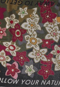 Tissu sombre avec des fleurs à cinq pétales multicolores en rouge, blanc, rose, vert et orange, et un texte partiel lisant « SUIVEZ VOTRE NATU ».