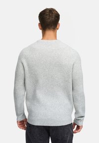 Maglione grigio chiaro a coste con colletto rotondo, maniche lunghe e una texture morbida, visto da dietro, abbinato a jeans scuri.