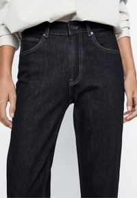 Tummat farkut suoran leikkauksen kanssa, etutaskut ja kontrastoiva beige ommel. Napillinen sulkeminen vyötäröllä, yksinkertainen ja monikäyttöinen muotoilu.