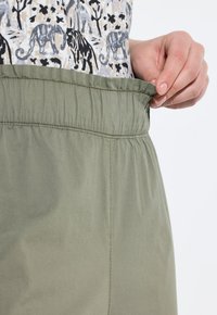 Groene elastische taillebandbroeken met een zachte, gladde textuur, voorzien van een geplooid ontwerp bij de taille voor comfort en aanpassingsmogelijkheden.