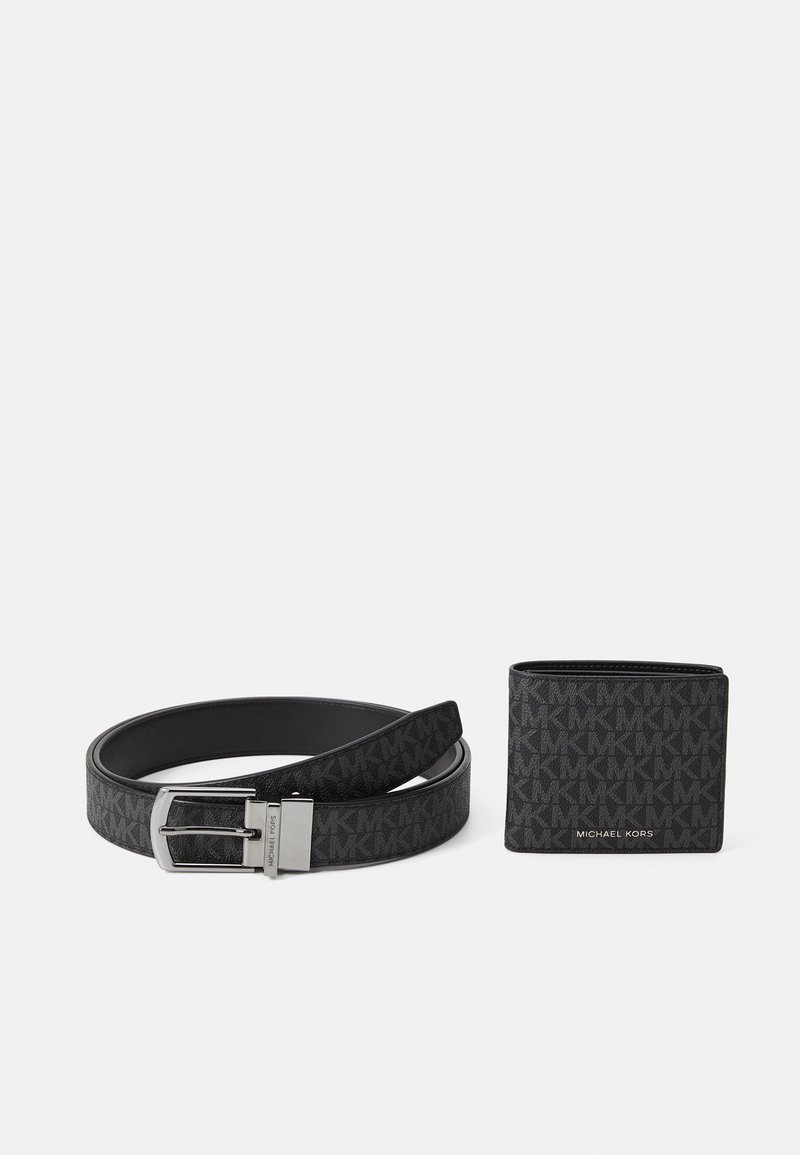 Cintura nera Michael Kors con fibbia argento e portafoglio nero abbinato con motivo a logo MK ripetuto, esposti su sfondo bianco.