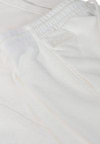 Pantaloni jogger bianchi realizzati in tessuto morbido, con vita elasticizzata e un piccolo etichetta testurizzata con "10 DAYS" vicino alla cucitura.