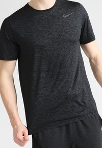 Czarny t-shirt Nike z krótkim rękawem, charakteryzujący się melanżową teksturą i okrągłym dekoltem. Dyskretny logo na górnej lewej części klatki piersiowej.