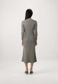 Robe en tricot grise longue et ajustée avec des manches longues et un ourlet évasé. Elle présente un col rond et des accents de boutons sur les manches.
