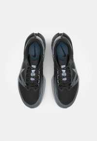 Baskets de sport noires avec des accents gris, tige en mesh, conception à lacets et semelle intérieure rembourrée, avec un logo swoosh sur la languette.
