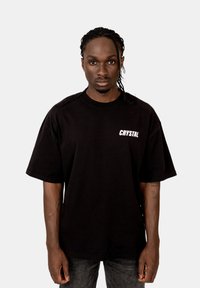 Černé oversized tričko z bavlny, s krátkými rukávy a bílým logem "CRYSTAL" na levé straně hrudi.