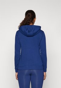 Felpa blu realizzata in tessuto morbido, con cappuccio regolabile, maniche lunghe e design aderente. Nessun motivo o accento visibile.