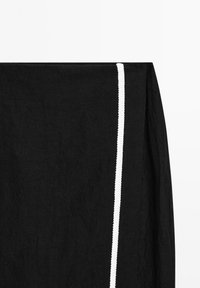 Černá lněná látka s texturovaným povrchem, zdobená vertikálním bílým propletem podél jedné strany. Jednoduchý a minimalistický design.