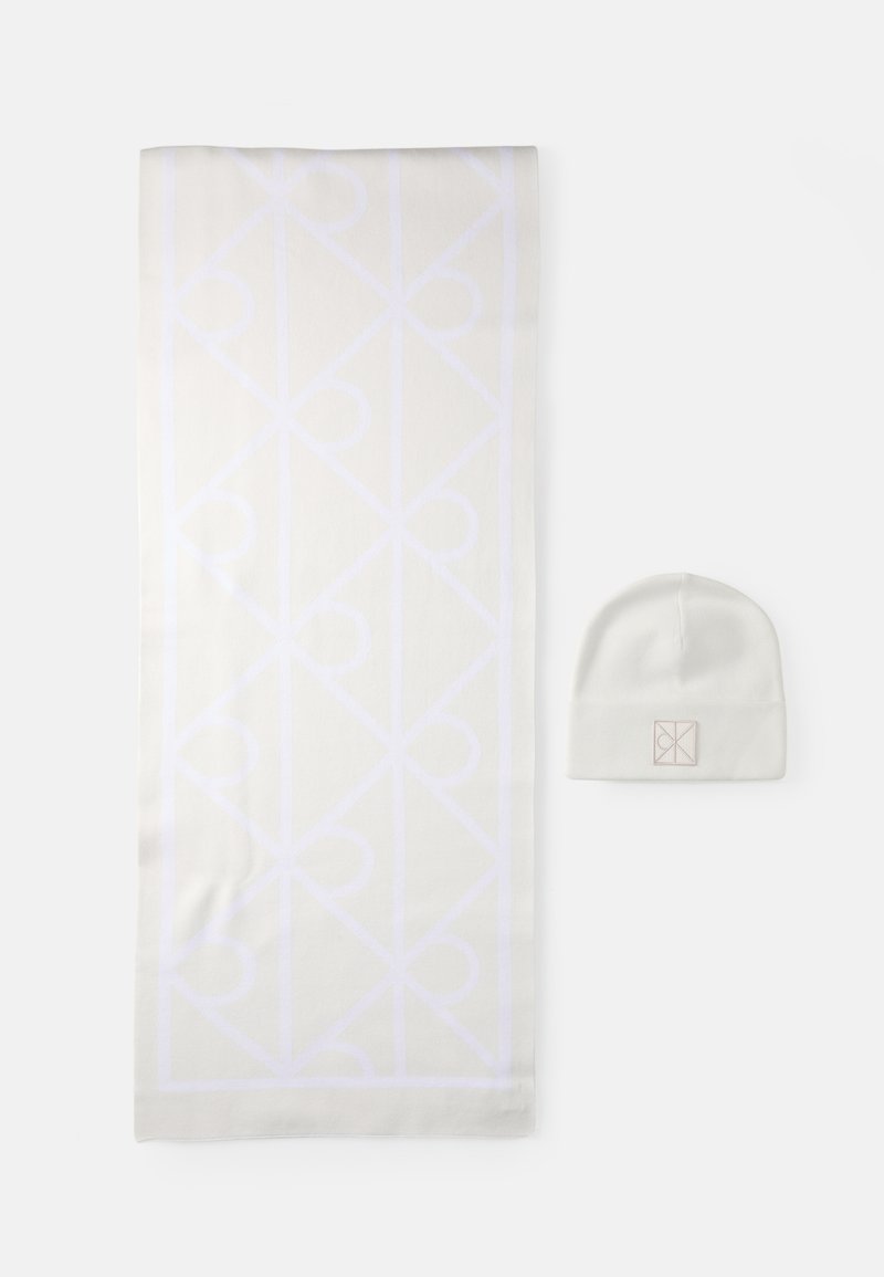 Cachecol branco com um padrão geométrico subtil e um gorro branco combinando com um logotipo minimalista em um tom claro.