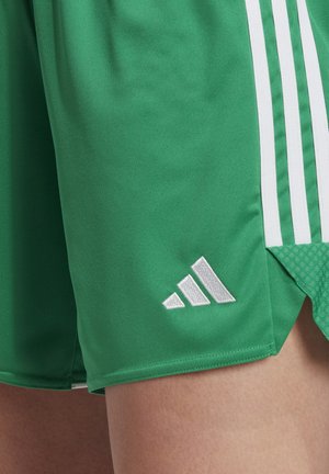 Green athletic shorts with white Adidas stripes, featuring a textured mesh panel and a small silver logo at the hem.