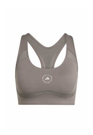 Grå hættetrøje med lynlås lagdelt over en brun sports-bh og matchende leggings. Lyserøde og sorte sneakers. Lille sort taske fastgjort i taljen.