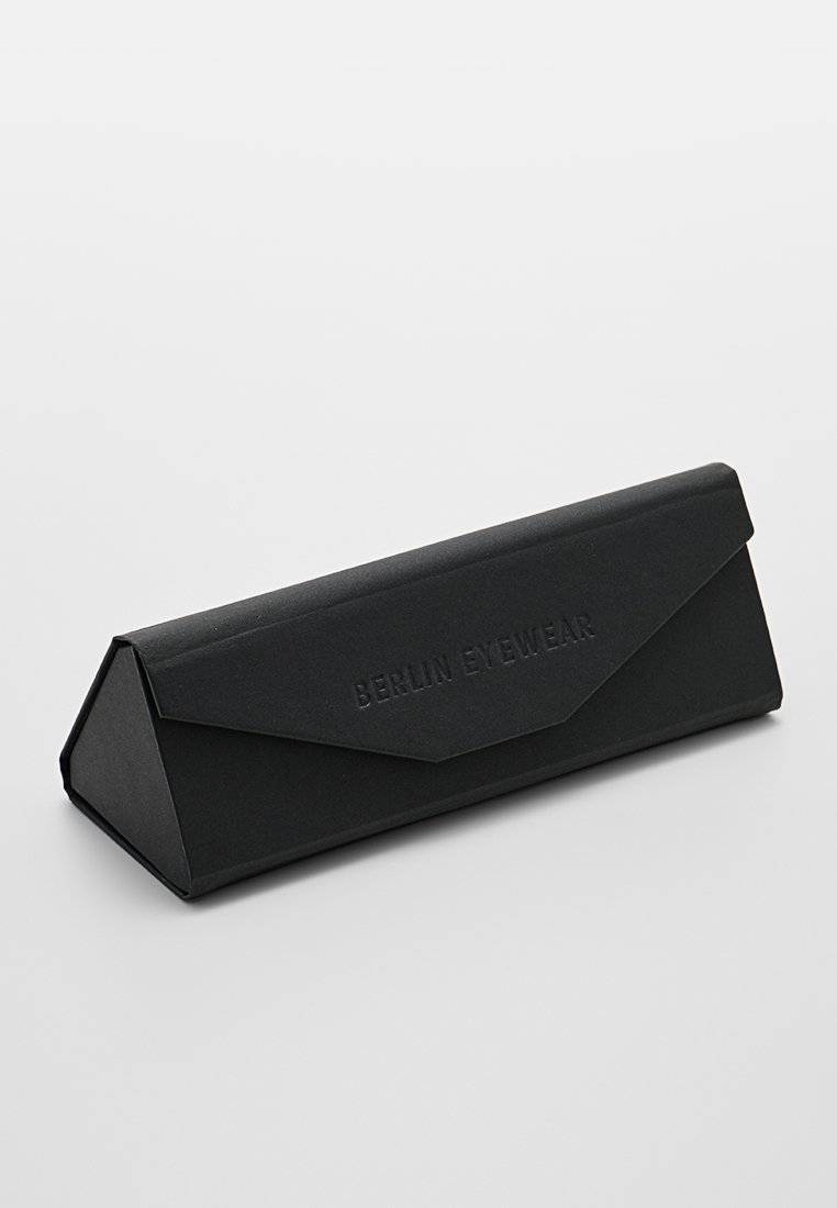 Estuche negro triangular para gafas, fabricado con cartón texturizado, con un logo en relieve "BERLIN EYEWEAR" en la parte frontal.