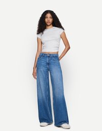Light gray fitted t-shirt paired with wide-leg blue jeans. Jeans feature a high waist, denim texture, and subtle stitching details.