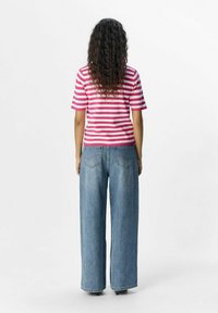 Chemise à manches courtes rayée rose et blanche, assortie à un jean en denim bleu clair à jambes larges. Présente une taille ajustée et une silhouette décontractée.