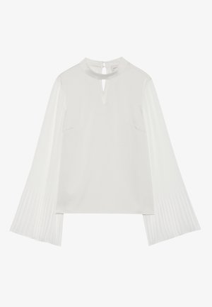 White top featuring a high neckline with a keyhole opening, soft fabric on the body, and pleated, textured fabric on the sleeves.