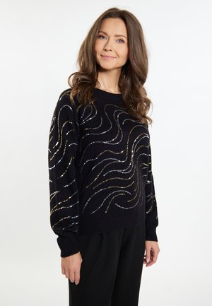 Pulover negru cu guler rotund, având un design cu modele texturate în forme de valuri din paiete argintii și aurii. Mâneci lungi cu manșete ribbate.
