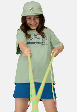 Lächendes Kind mit grünem Hut und Hemd, hält grünes und oranges Kletterseil, auf dem Hemd steht "You never climb alone."