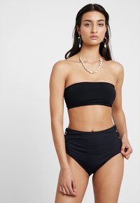 Čierny bandeau bikiny top s hladkou textúrou. Vysoko pásové bikiny s bočnými zlatými akcentmi. Jednoduchý, minimalistický dizajn.