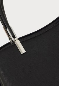 Sac à main en cuir noir avec une surface texturée, équipé d'un fermoir en métal argenté et d'un design à double bandoulière.